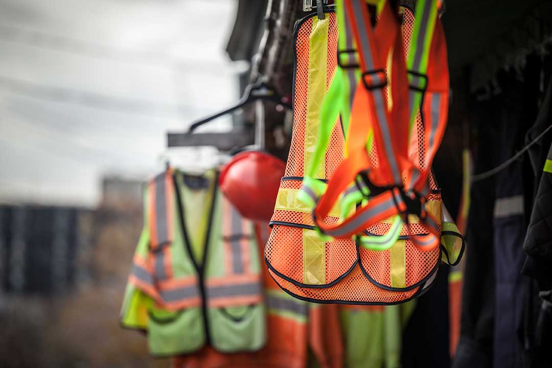Safety vests and helmets hanging on a line.