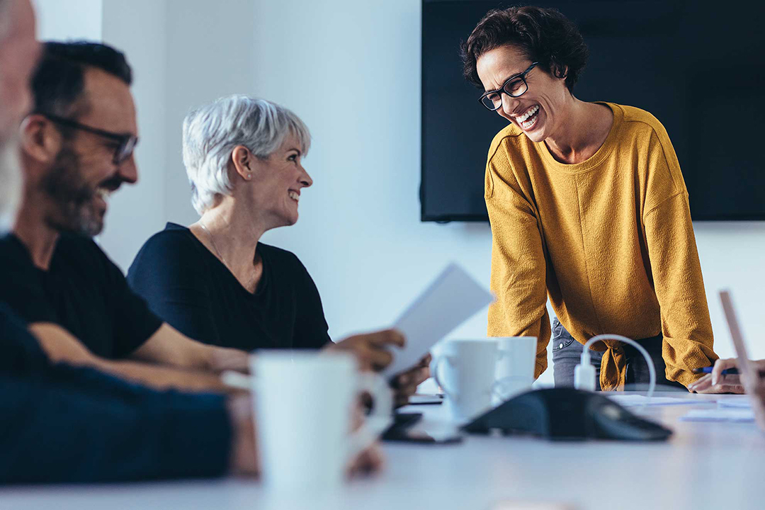 A group of three people have a meeting in a boardrrom like set up.